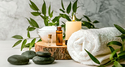 different items used in massage therapy gathered together on a wooden stand surrounded by plants