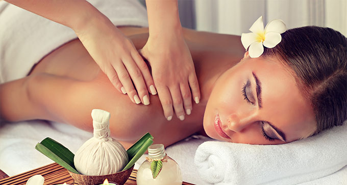 a woman enjoying a shoulder massage with a flower in her hair