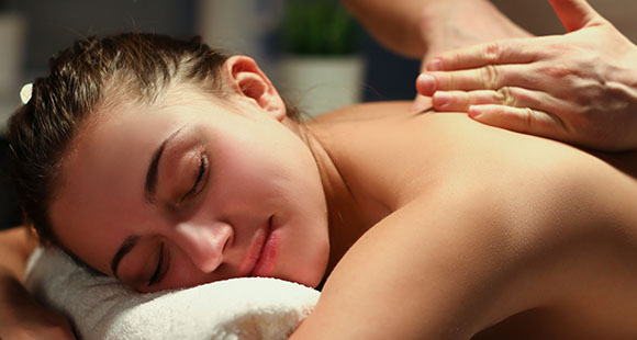 a woman receiving a back massage as a part of a full body massage