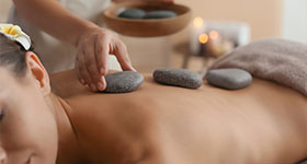 man experiencing a hot stone massage with a flower in her hair