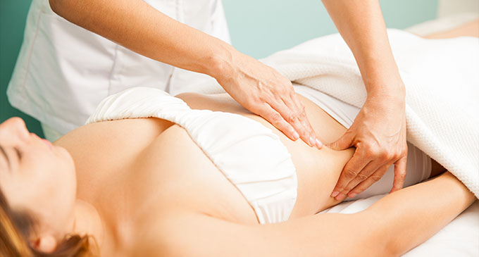 a woman receiving a lymphatic drainage massage to her abdomen