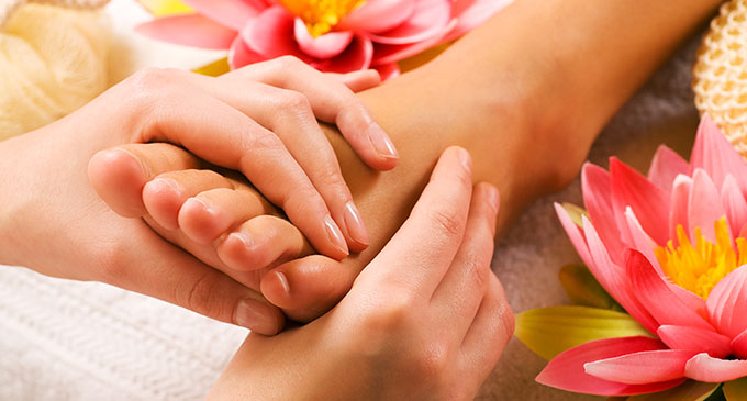 a woman receiving a foot massage with flowers adorned around 