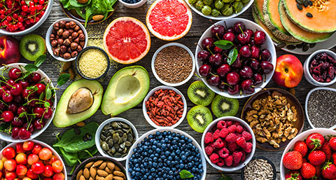 a selection of different fruits, vegetables and nuts on a wooden table