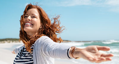 a woman with her arms spread out at the beach