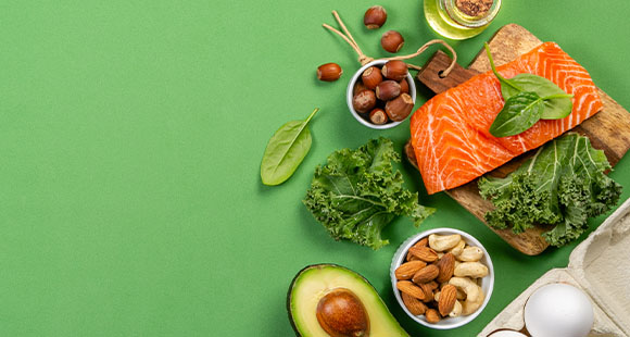 salmon, avocado, eggs, nuts, seeds and greens on a green background