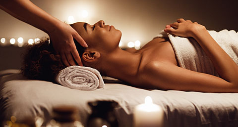 a woman enjoying a relaxing massage, laid down in a candle-lit room